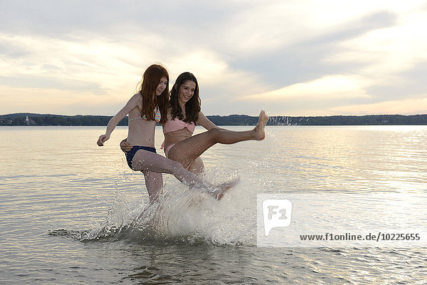 Germany  Upper Bavaria  Lake Starnberg  two girls splashing with water