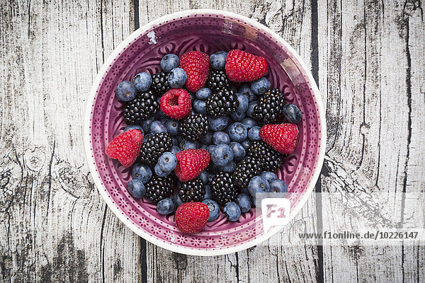 Bowl of different wild berries on wood
