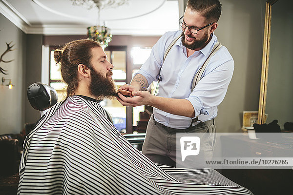 Barber brushing beard of a customer