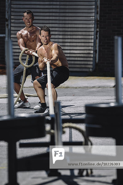 Two CrossFit athletes pulling rope