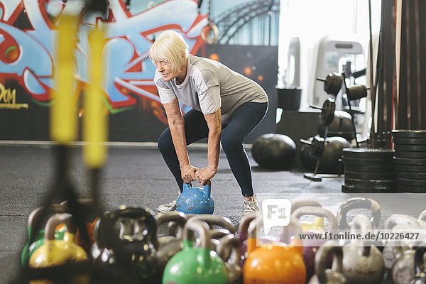 Senior woman in gym lifting kettlebell