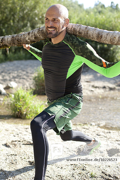 Mann beim CrossFit Training mit Baumstamm auf den Schultern