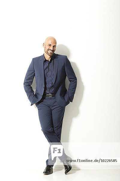 Portrait of bald man with beard wearing blue suit in front of white background