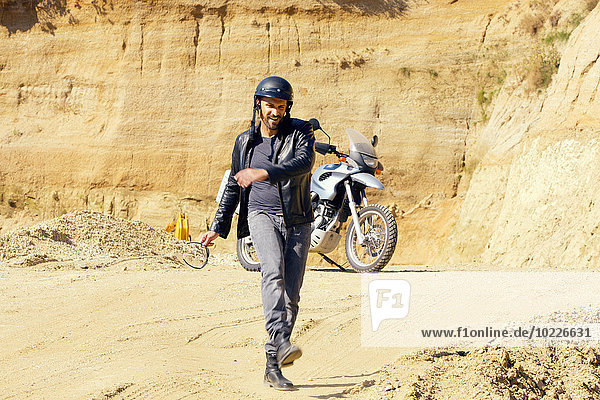 Mature man with motor bike in sand pit