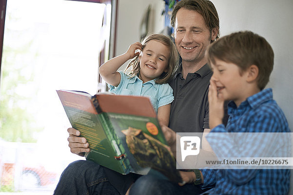 Vater liest seinen Kindern ein Buch vor