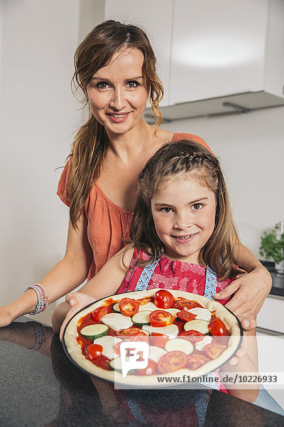 Mutter und Tochter präsentieren hausgemachte Pizza