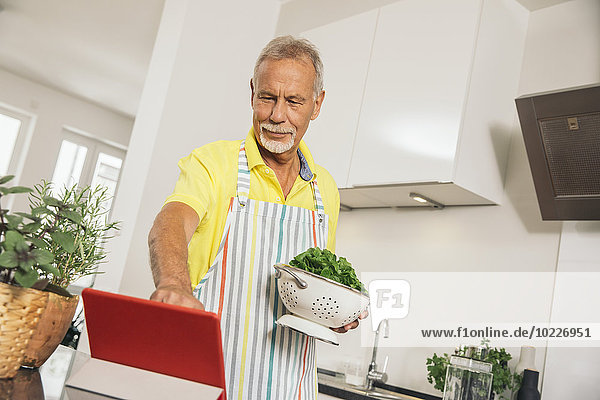 Mann mit digitalem Tablett in der Küche