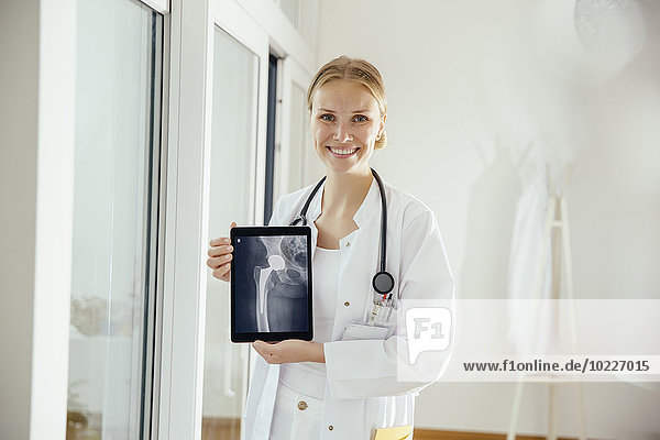Portrait of smiling female doctor showing an x-ray on digital tablet