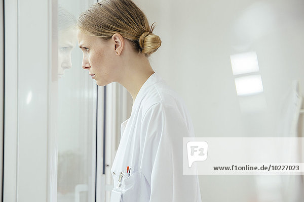 Serious female doctor looking out of window