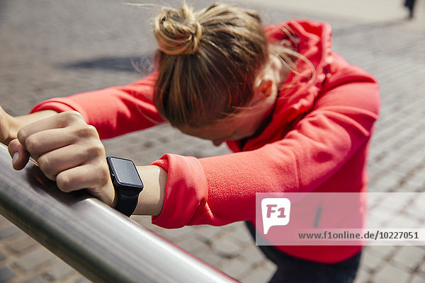 Young sporty woman with smart watch stretching