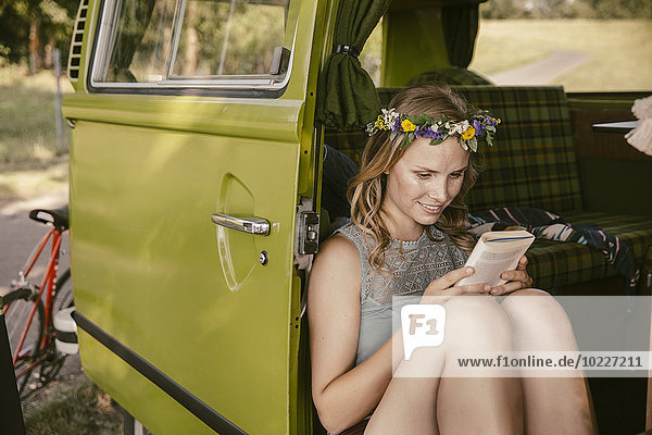 Hippie-Frau beim Lesen eines Buches im Van
