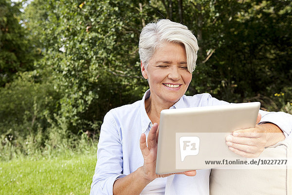 Lächelnde reife Frau im Freien mit digitalem Tablett