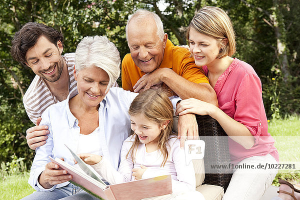 Glückliche Großfamilie mit Buch im Freien