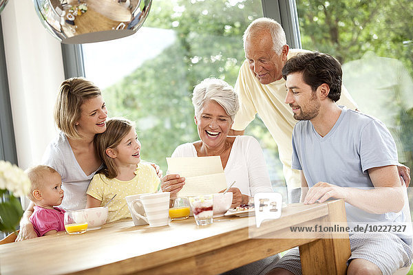 Glückliche Enkelin mit ihrem Familien-Lesebrief am Frühstückstisch