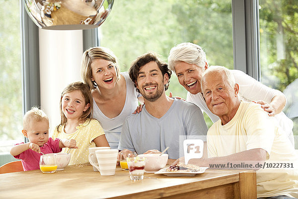Porträt einer glücklichen Großfamilie am Frühstückstisch