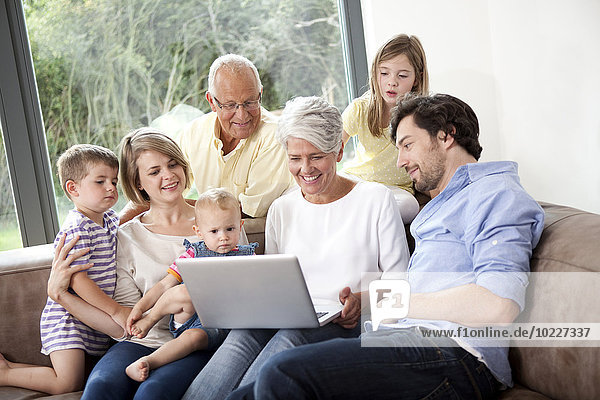 Extended family on couch using laptop