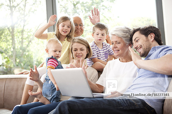 Großfamilie auf Couch mit Videokonferenz