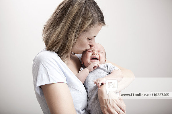 Young woman kissing crying baby