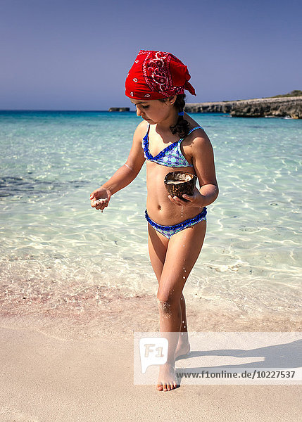 Spain  Balearic Islands  Menorca  little girl playing on the beach with a coconut husk