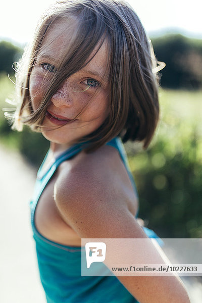 Porträt eines lächelnden Mädchens mit braunen Haaren und Sommersprossen