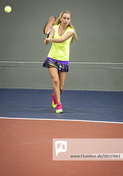 Junge Frau beim Tennisspielen in einer Tennishalle