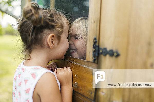 Spanien  Asturien  Gijon  Kleine Mädchen beim Spielen durch ein Glasfenster