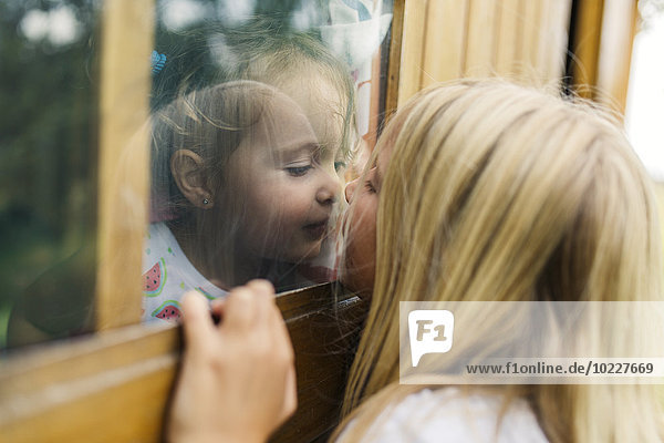 Spain  Asturias  Gijon  Little girls playing through a glass window