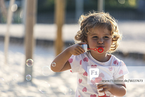 Kleines Mädchen macht Seifenblasen auf dem Spielplatz