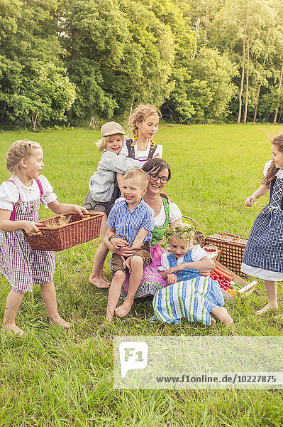 Deutschland  Sachsen  Kinder und deren Erzieher in traditioneller Kleidung auf einer Wiese