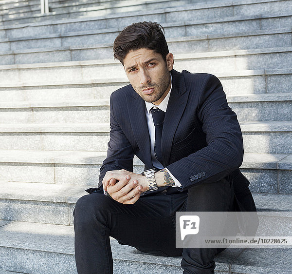 Portrait of young businessman sitting on the stairs