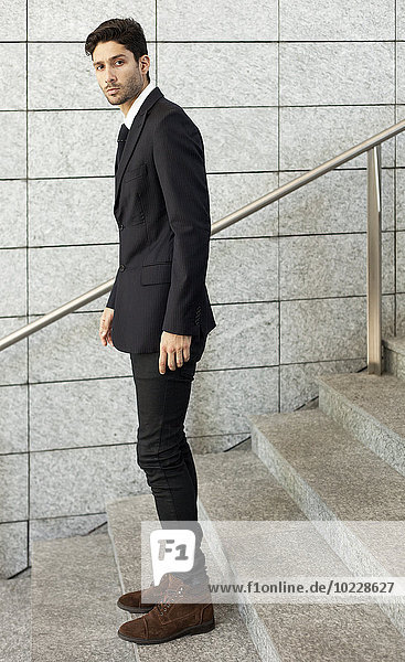 Porträt eines jungen Geschäftsmannes  der auf der Treppe steht