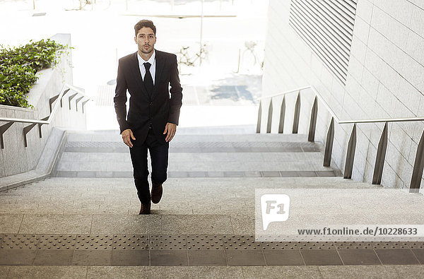 Portrait of young businessman walking up the stairs