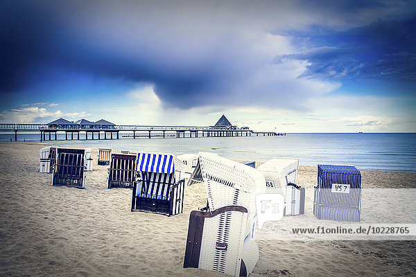 Deutschland  Heringsdorf  Blick auf Seebrücke mit Kapuzenstühlen am Strand im Vordergrund