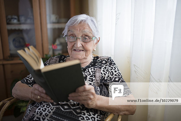 Seniorin beim Lesen eines Buches zu Hause