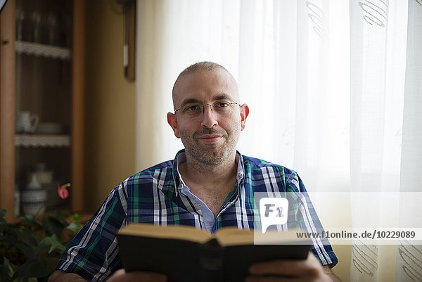 Porträt eines Mannes mit Buch zu Hause