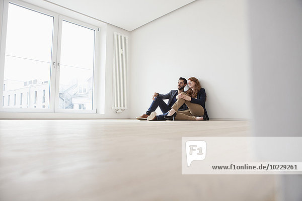 Young couple sitting on floor of their new flat