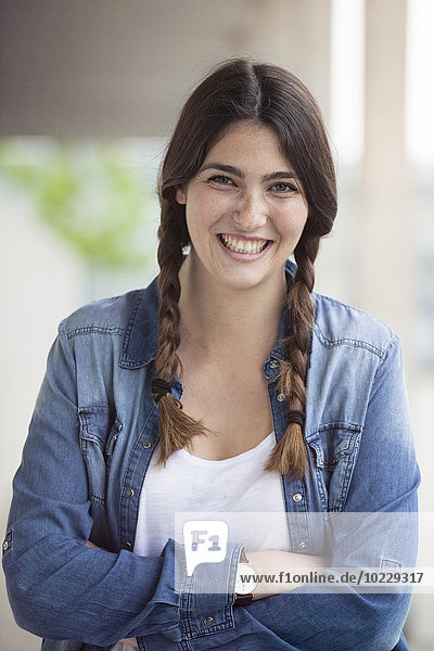 Porträt einer lächelnden jungen Frau mit Zöpfen