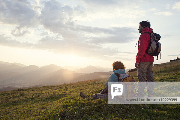 Österreich  Tirol  Unterberghorn  zwei Wanderer in alpiner Landschaft bei Sonnenaufgang