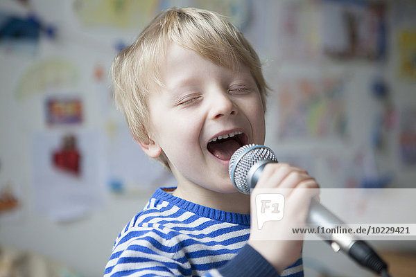 Portrait of singing little boy with microphone