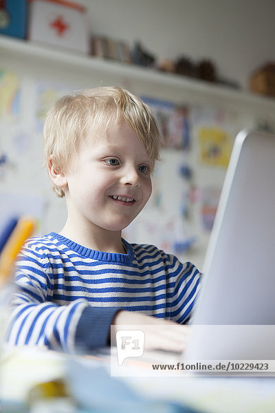 Portrait of smiling little boy using laptop