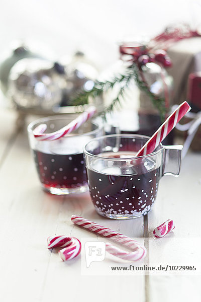 Gläser Glühwein,  Zuckerstangen und Weihnachtsdekoration