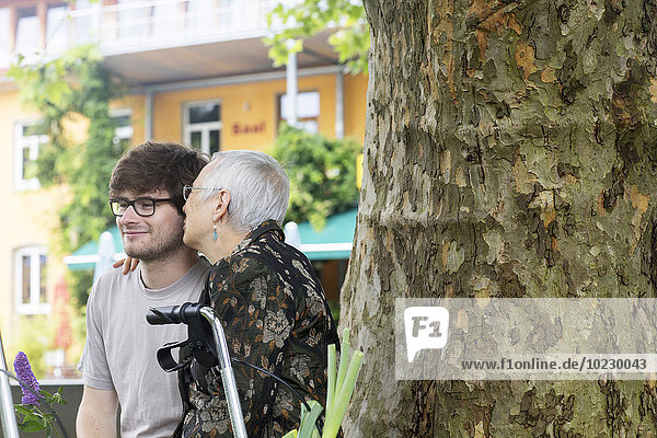 Senior woman embracing young man at tree