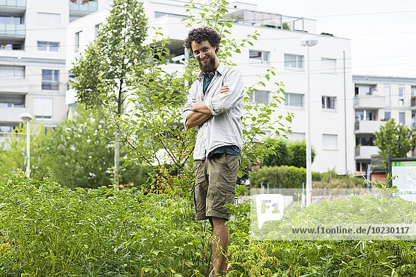 Junger Mann steht in einem städtischen Garten
