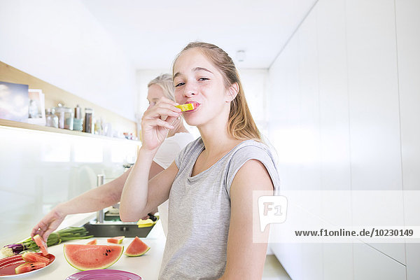 Portrait of smiling teenage girl eating melon in the kitchen
