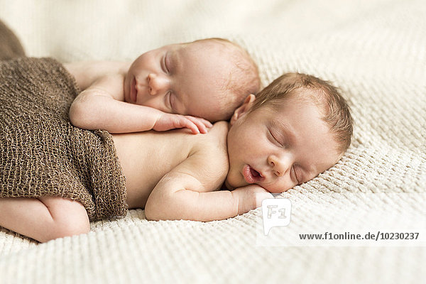 Neugeborene Zwillinge mit einem Tuch bedeckt  das auf einer Decke schläft.