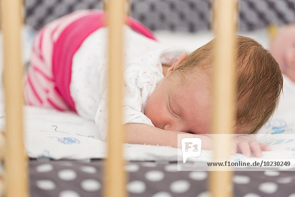 Neugeborenes Mädchen schläft auf dem Kinderbett