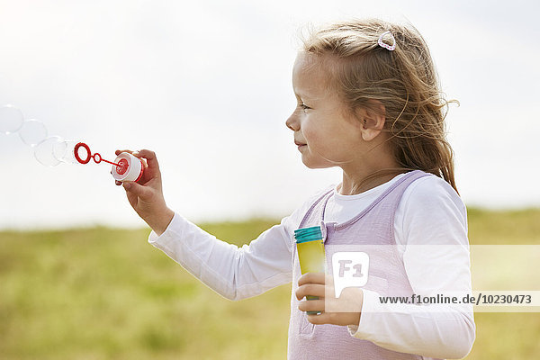 Little children girl blowing soap bubbles