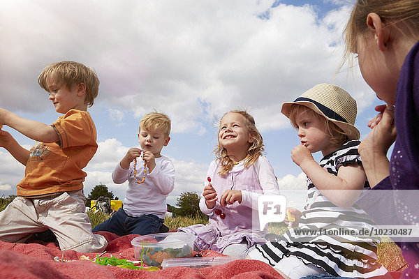 Children sitting on a blanket eating sweets