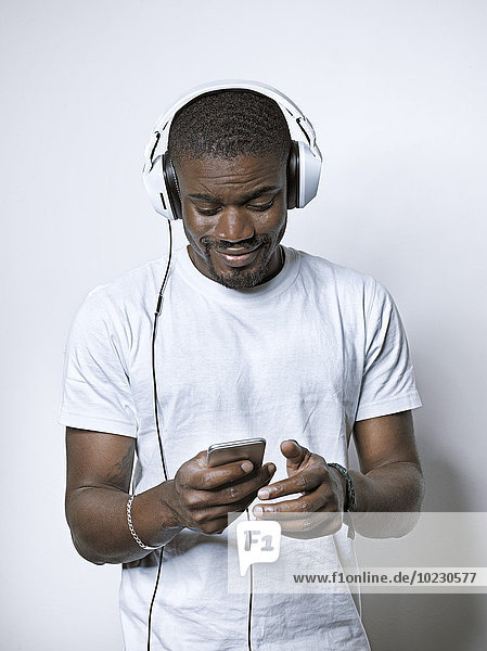 Smiling young man with headphones looking at cell phone