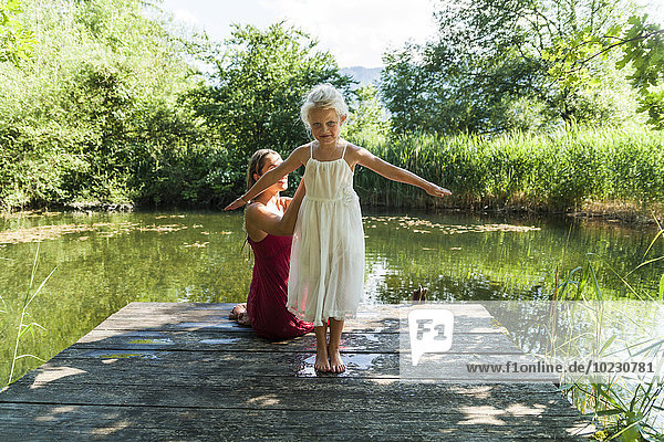 Mädchen mit Mutter am Steg am See
